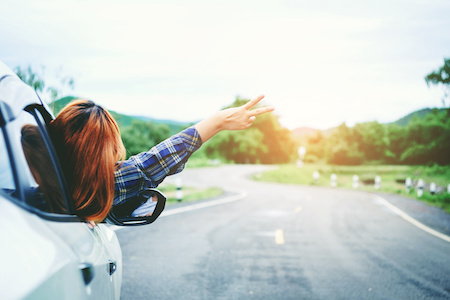 Relaxed happy woman traveler on summer roadtrip vacation on hatchback ca